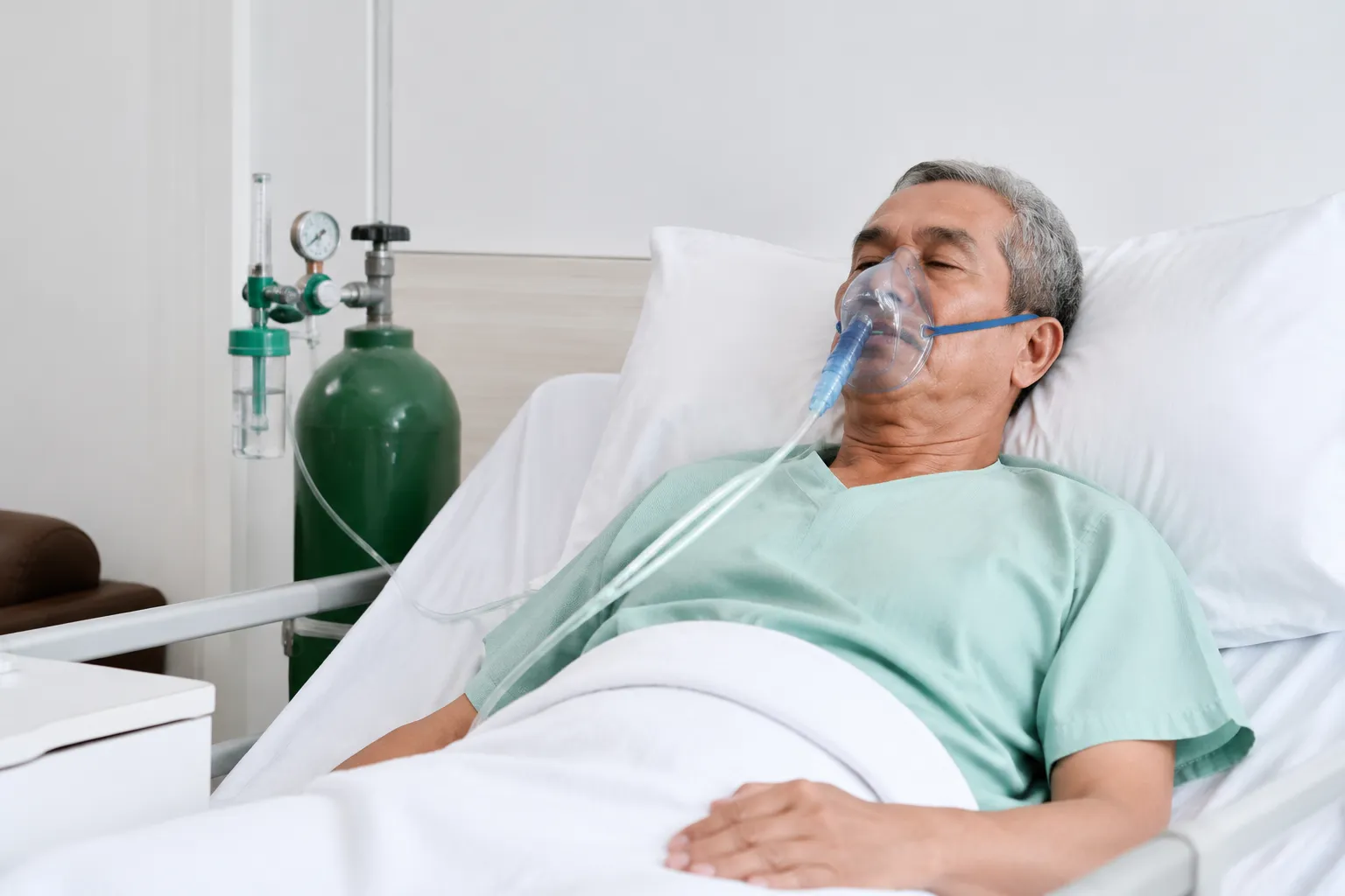 Acute HDU bay showing a pneumonia patient receiving NIV mask treatment alongside pulse oximeter, inf