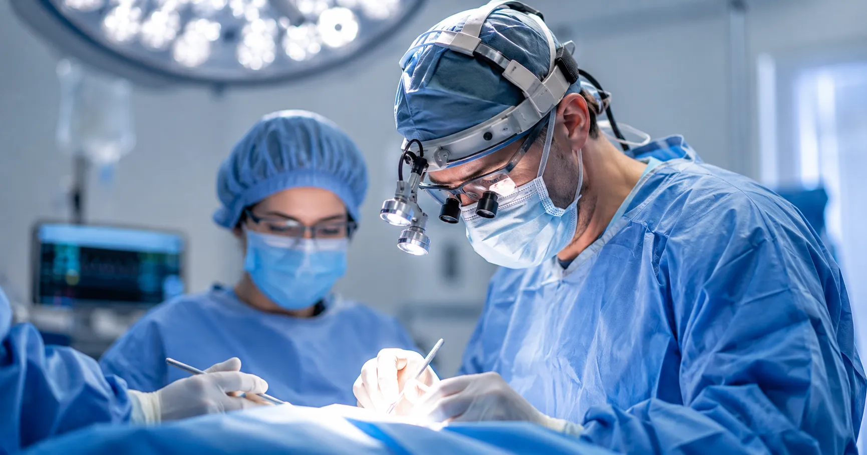 Surgeon wearing an LED surgical headlight during a precision operating room procedure