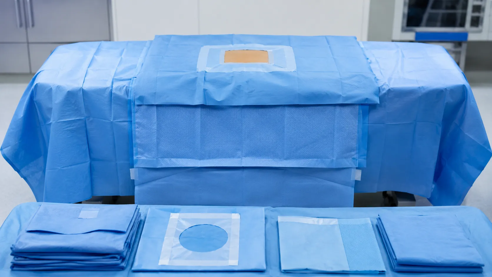 Scrub team applying a fenestrated surgical drape to build the sterile field around a patient in thea