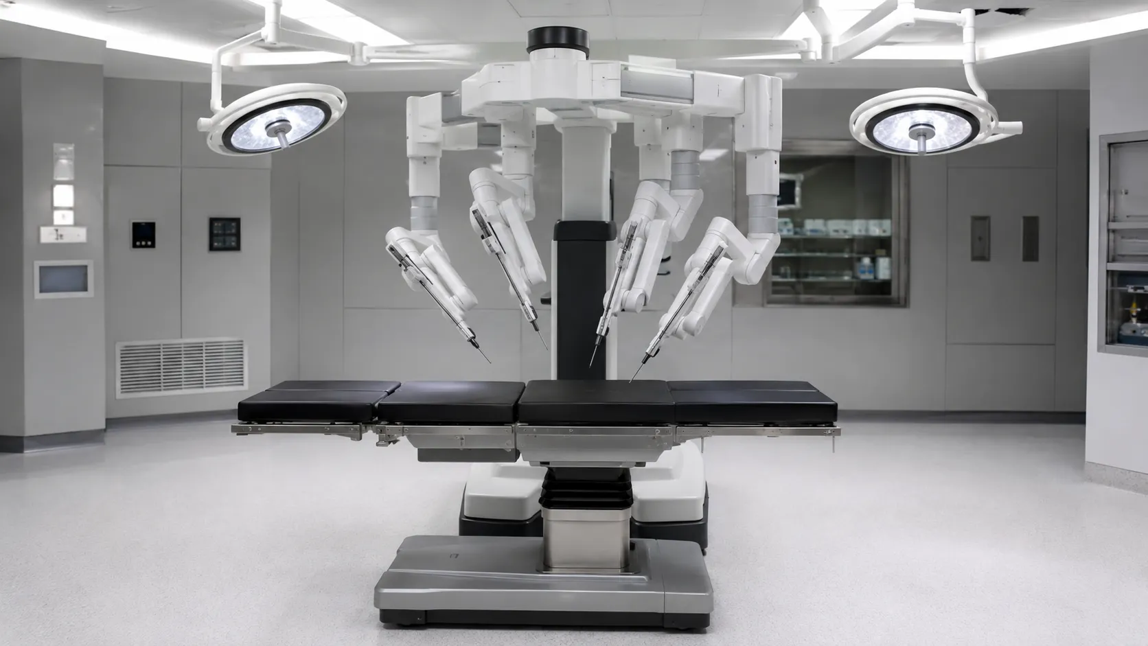Surgeon seated at a robotic surgery console controlling robotic arms docked to a patient in theatre